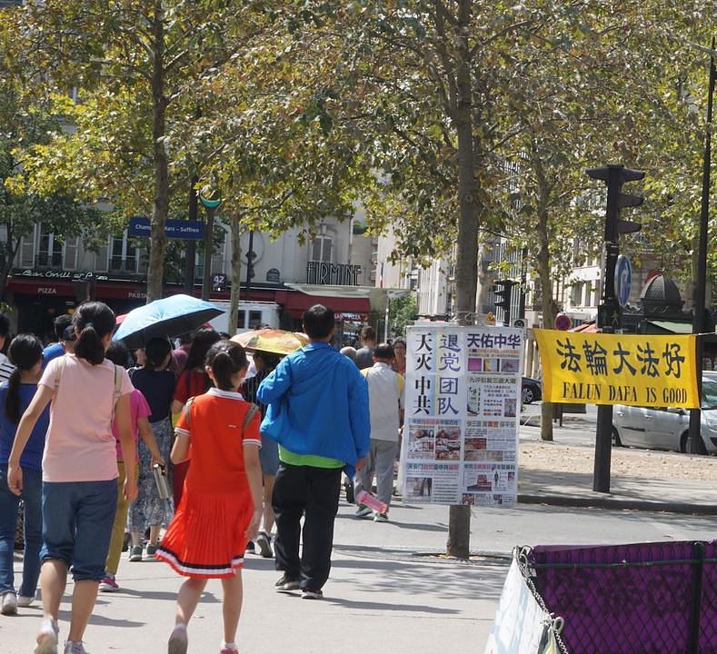 Kineski turisti razgledaju Falun Gong plakate i transparente u šetnji po Parizu.