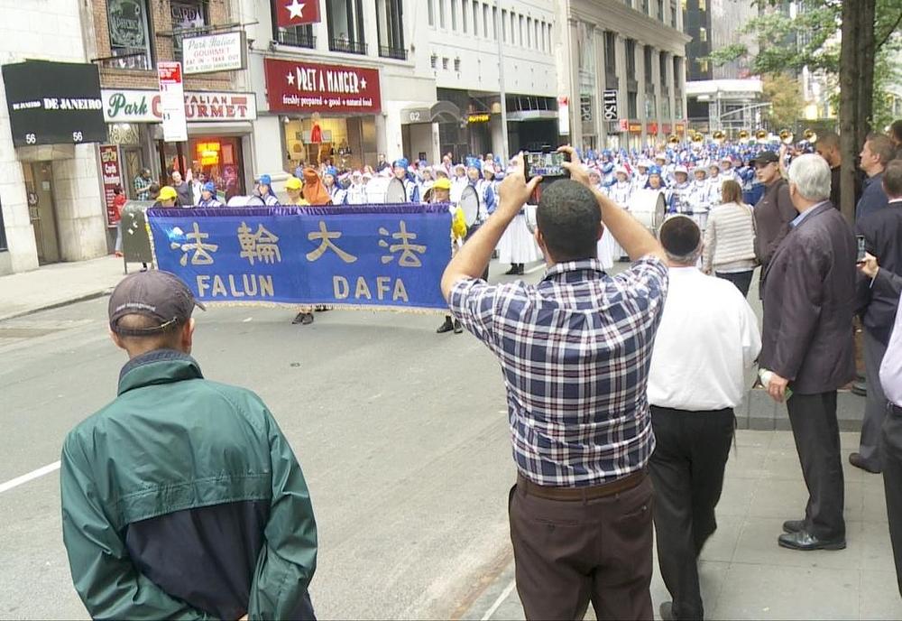 Gledaoci parade snimaju fotografije i video zapise nastupa Tian Guo Marching Band-a na paradi.