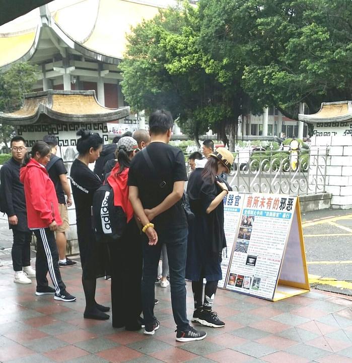 Turisti čitaju plakate ispred Nacionalne memorijalne dvorane Sun Yat-sen u Tajpeju.
