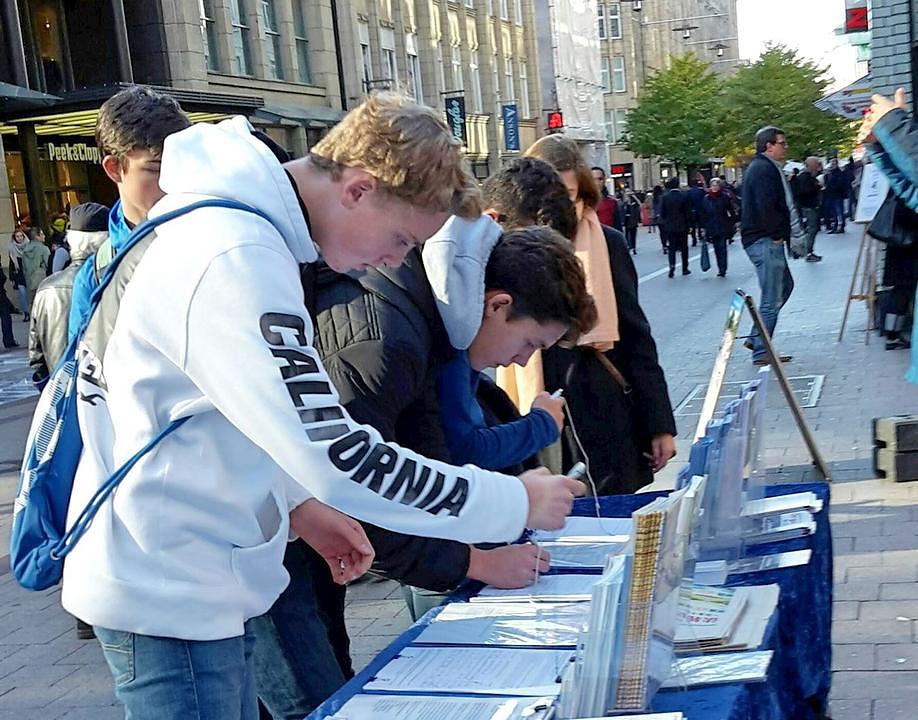 Četvoro mladih ljudi se informiraju Falun Dafa te potpisuju peticiju
 