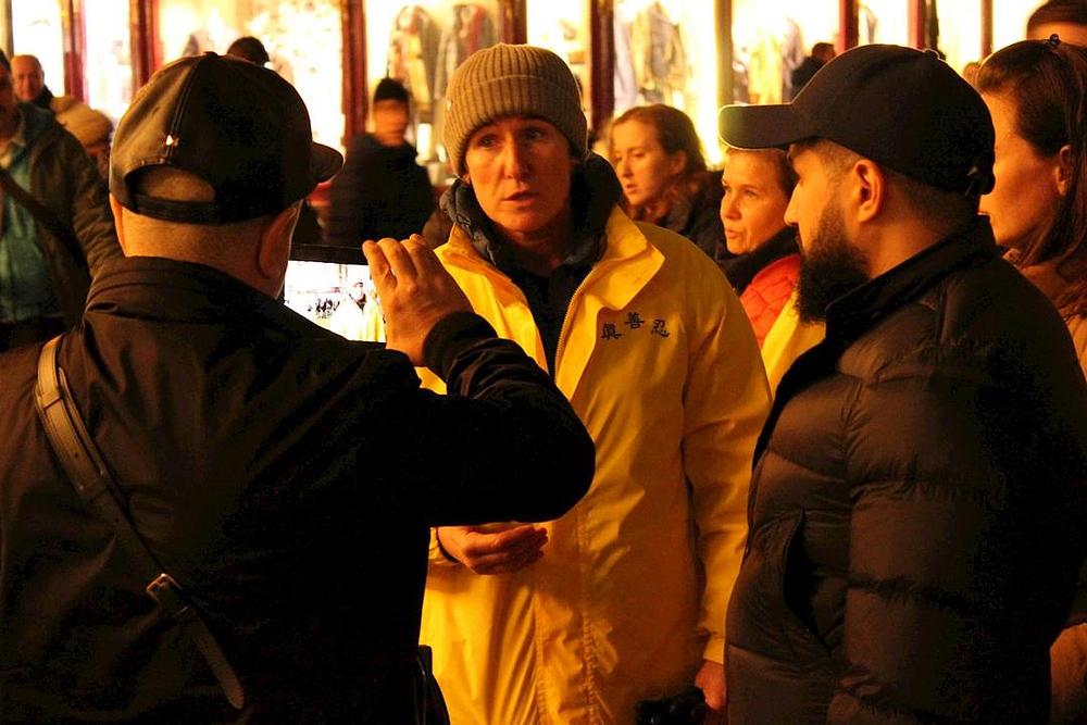 Ruski turist snima video dok praktikant objašnjava što je Falun Gong i koja je svrha bdijenja uz svijeće.