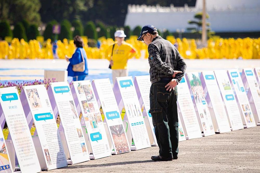 Posjetioci na Trgu slobode čitaju izložene Falun Dafa panele.