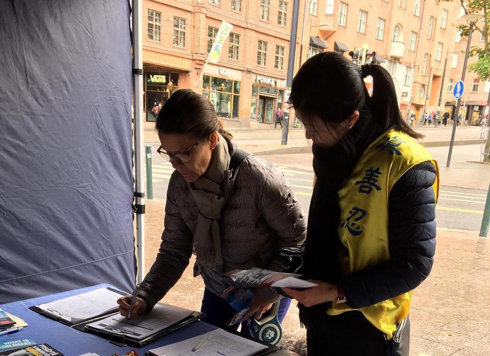Ljudi potpisuju peticiju kojom se osuđuje progon Falun Gonga u Kini.