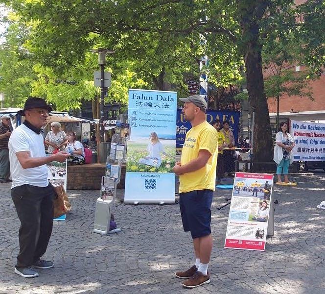Prolaznici se zaustavljaju da bi saznali više o Falun Dafa.