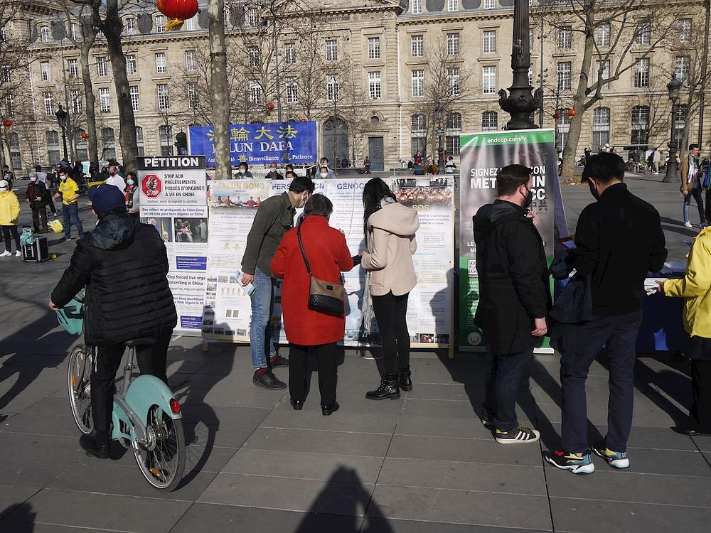 Prolaznici se zaustavljaju ispred izložbenih panoa koje su postavili praktikanti na Place de la République i informišu se o Falun Dafa i tekućem progonu u Kini 