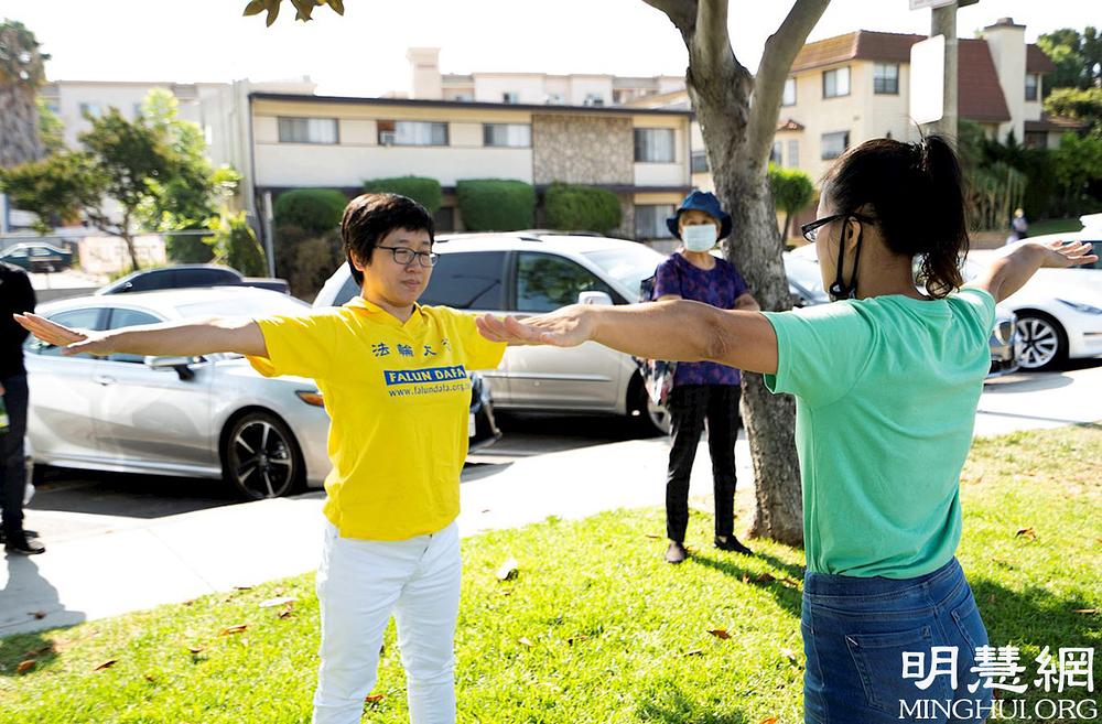 Prolaznik prije skupa uči Falun Dafa vježbe.