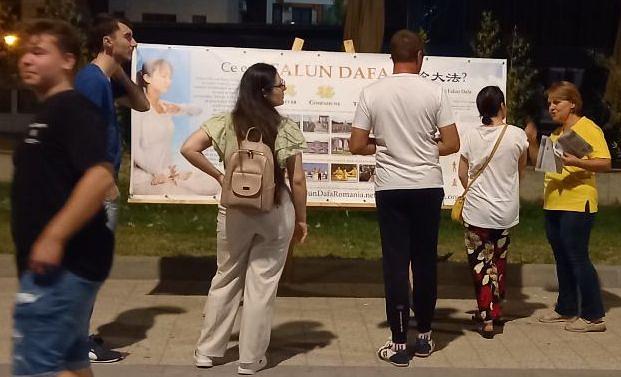 Ljudi u Mamaiu, 12. avgusta, čitaju plakate i postavljaju pitanja o Falun Dafa.