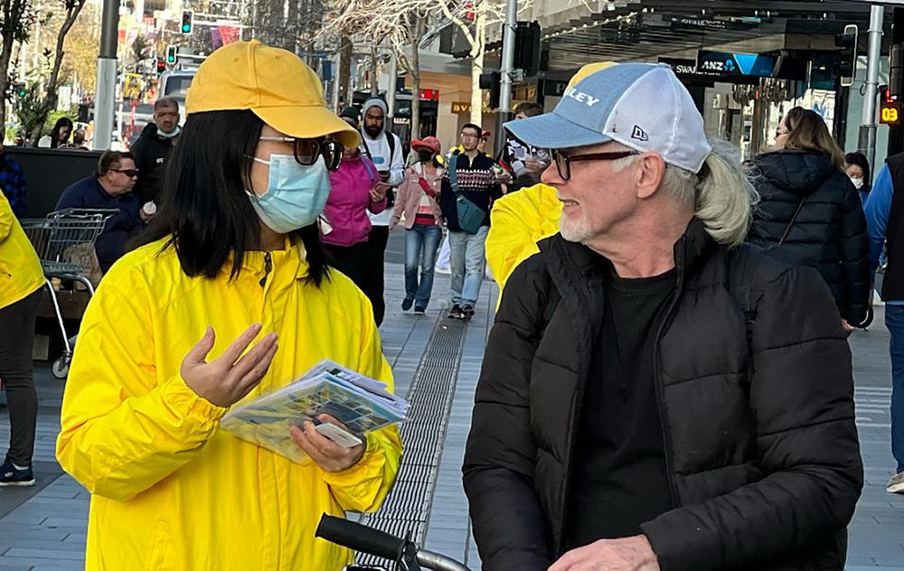 Praktikant razgovara s prolaznikom o Falun Dafa. 
