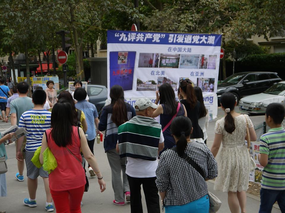 Kineski turisti u Parizu prolaze pored informativnih plakata Falun Gonga o globalnom pokretu istupanja iz Kineske komunističke partije.