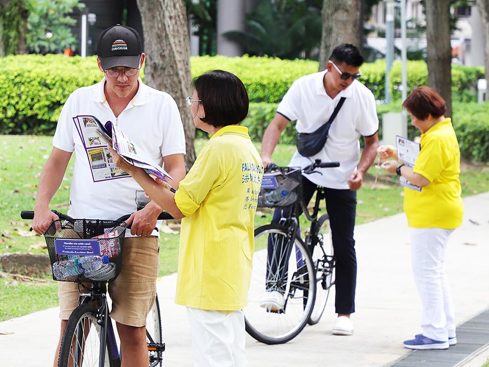 Prolaznici se zaustavljaju da bi saznali više o Falun Dafa.
