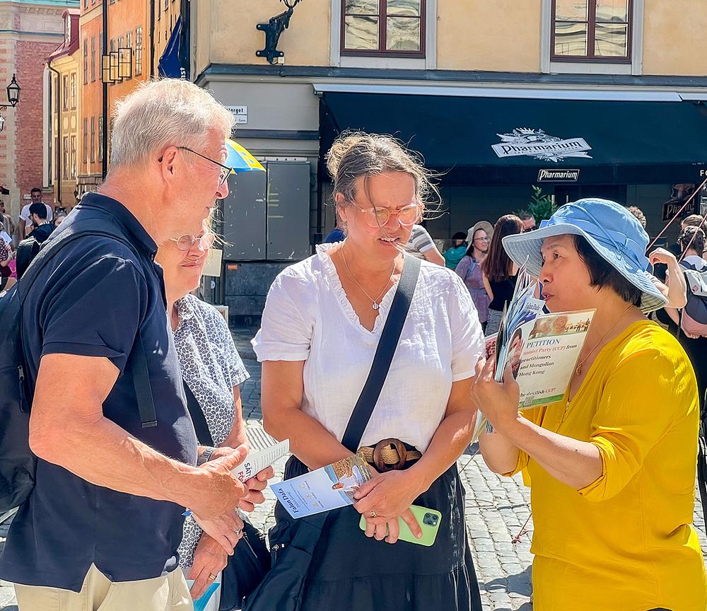 Ljudi razgovaraju s praktikantima o Falun Dafa i o progonu.