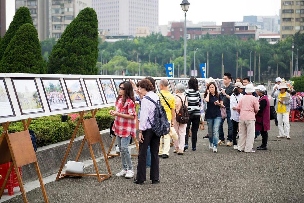 Posjetioci razgledaju izložbu fotografija o Falun Gongu.