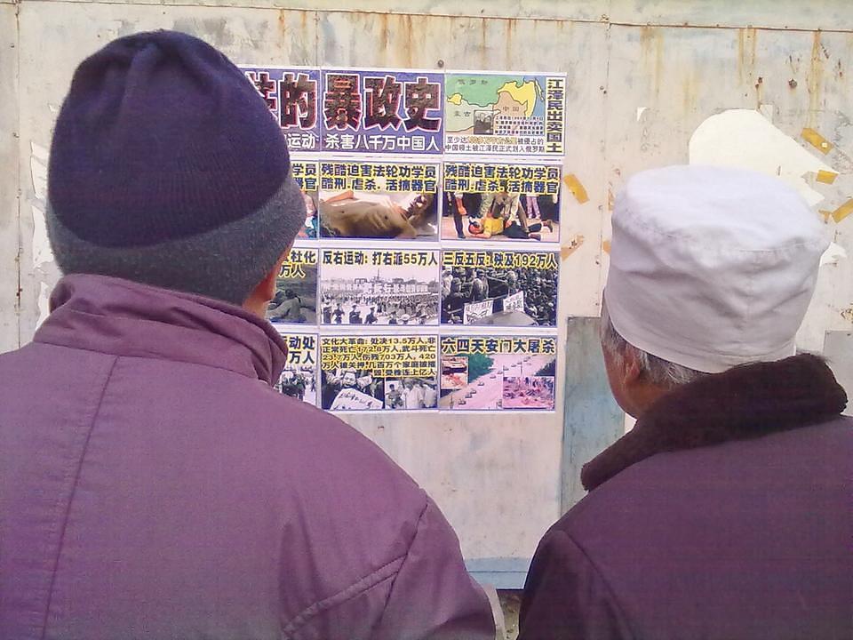 Par čita plakat u gradu Zhangjiakou u provinciji Hebei.