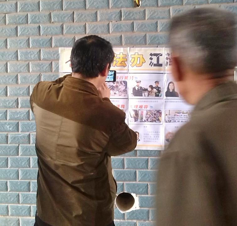 Jedna osoba čita plakat u gradu Nanchongu u provinciji Sichuan u Centralnoj Kini, dok druga fotografiše.