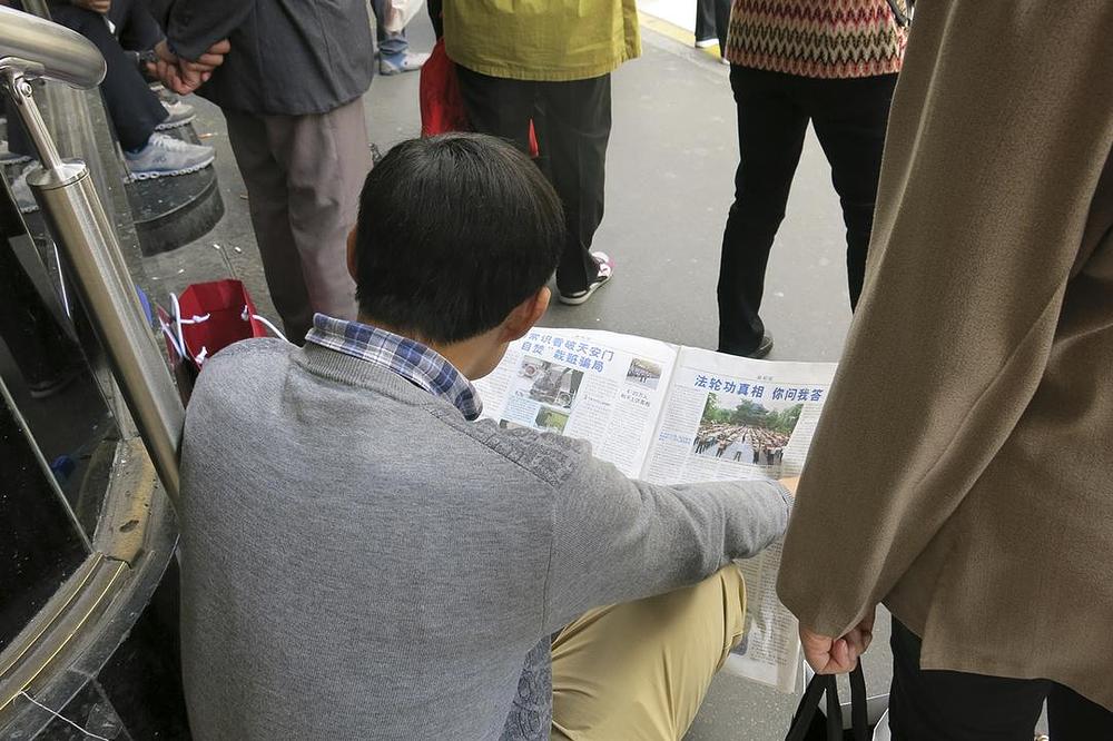 Turisti iz Kine čitaju informativne materijale ispred Galeries Lafayette.