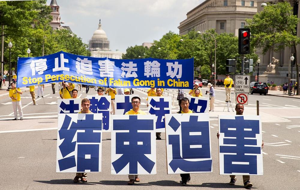 Praktikanti Falun Gonga u povorci u Wašingtonu 14. jula 2016. godine u znak protesta protiv progona Falun Gonga od strane kineskog komunističkog režima. Četiri praktikanta na čelu povorke drže transparent na kome piše: „Zaustavite progon“.
