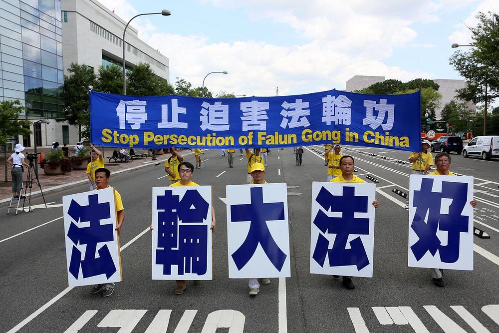Pet praktikanata drže veliki transparent sa natpisom „Falun Dafa je dobar“.