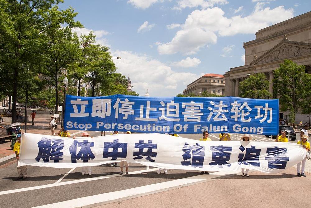 Bijeli transparent na čelu nosi natpis: „Raspustite Kinesku komunističku pariju i zaustavite progon“.
