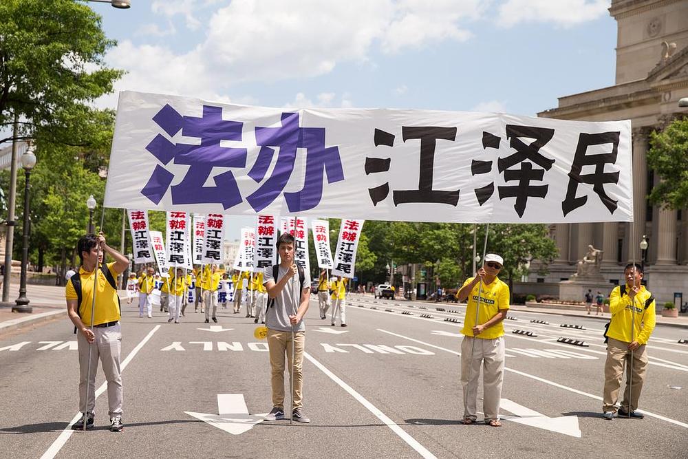 Na velikom transparentu piše: „Dovedite Jiang Zemina pred lice pravde“. Jiang Zemin, bivši šef Kineske komunističke partije, je pokrenuo progon Falun Gonga 1999. godine.