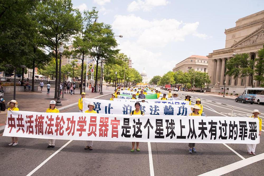 Transparent na čelu nosi natpis: „Žetva organa uzimanih od živih praktikanta Falun Gonga koju vrši KKP je oblik zla do sada ne zabilježen na planeti“.