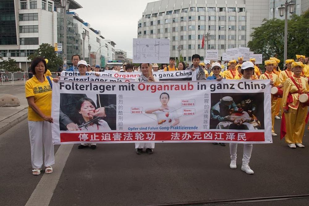 Veliki transparent sa slikama i informacijama o žetvi organa uzetih od živih praktikanata Falun Gonga koju vrši KKP. Na transparentu piše: „Zaustavite progon Falun Gonga. Dovedite Jiang Zemina pred lice pravde.“