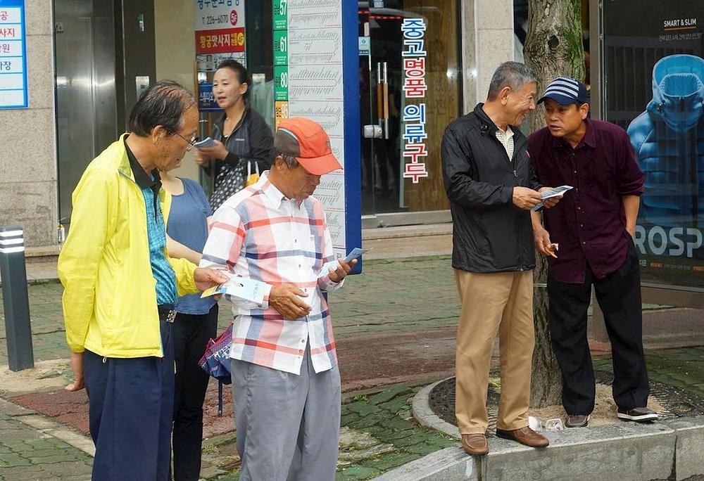 Prolaznici čitaju letke o Falun Dafa i progonu u Kini.