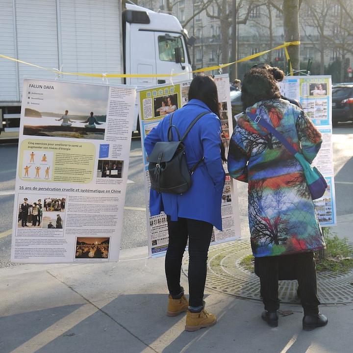 Kineski turisti čitaju izložene Falun Gong plakate.