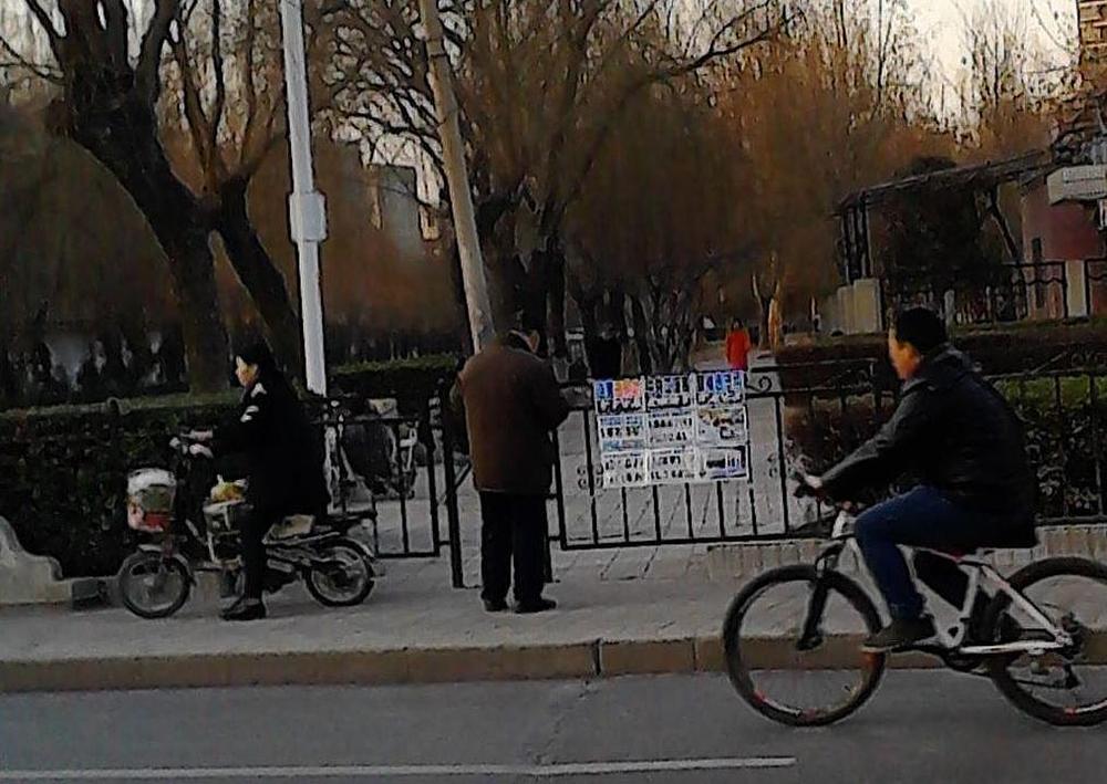 Prolaznici čitaju o tome kako KKP progoni Falun Gong.