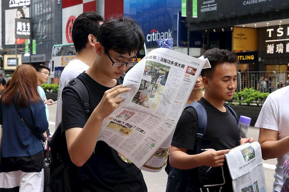 Kineski turisti čitaju Falun Gong novine 