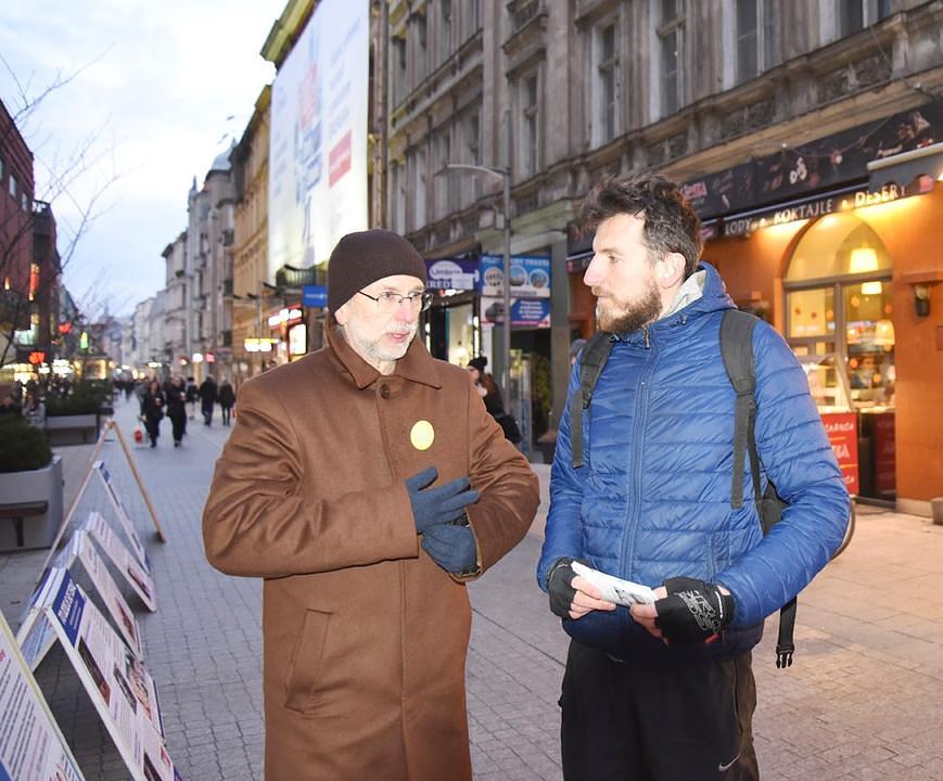 Maciej Kędelski (desno) sluša praktikanta koji mu govori o progonu. On je uzeo dosta letaka da ih podijeli prijateljima i porodici.