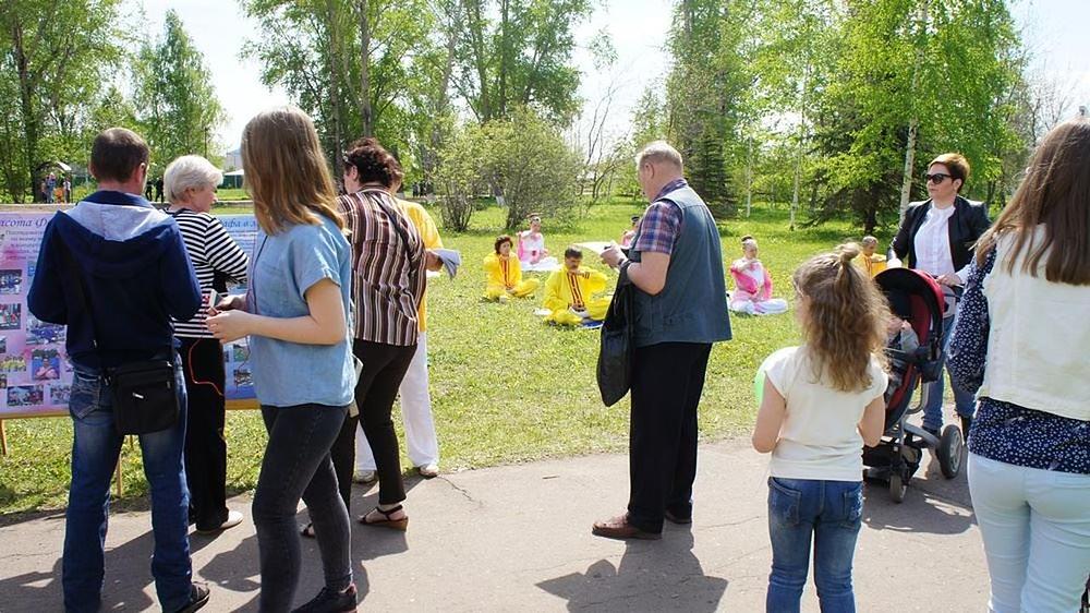 Prolaznici uče o Falun Gongu dok gledaju praktikante kako meditiraju.