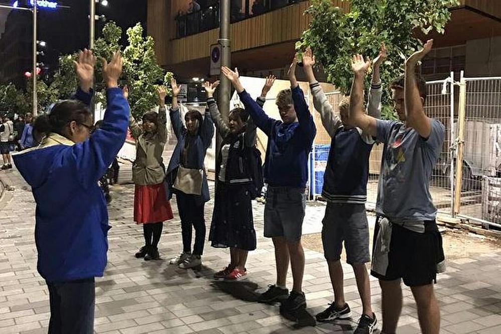 Prolaznici uče Falun Dafa vježbe. 