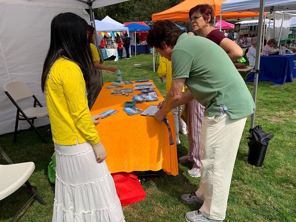 Ljudi se zaustavljaju pored praktikantskog štanda da bi saznali  više o Falun Gongu.