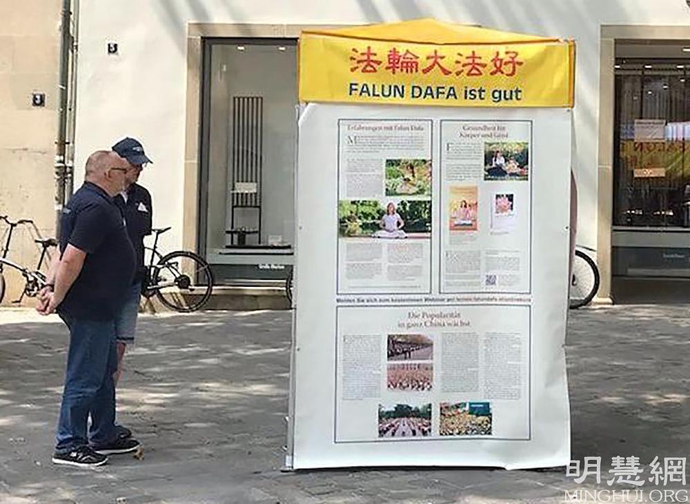 Dva prolaznika čitaju informativne panele.