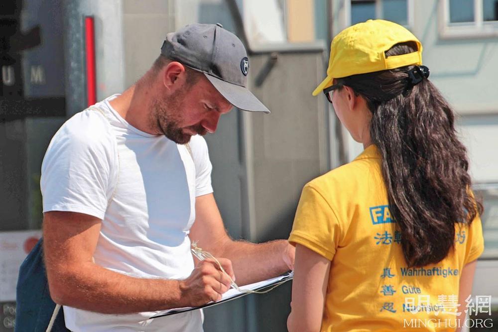 Prolaznik potpisuje peticiju za osudu progona u Kini
 