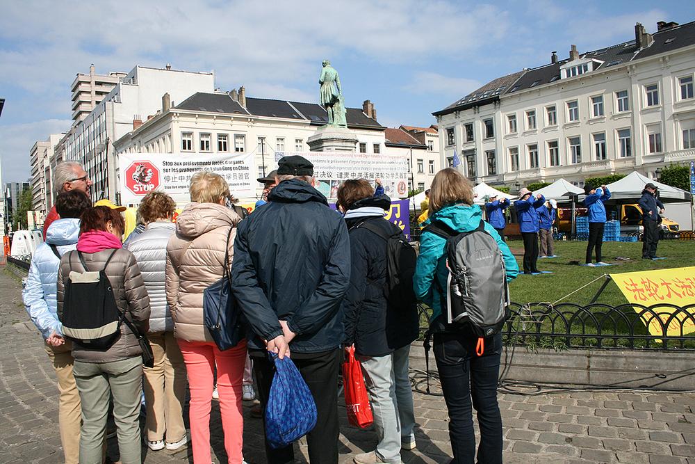 Prolaznici promatraju kako Dafa praktikanti rade vježbe.