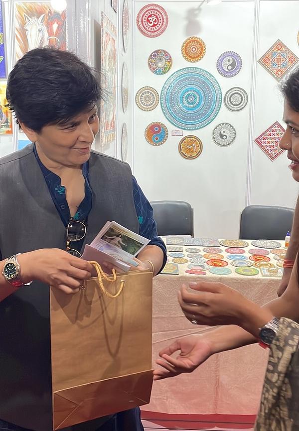 Pjevačica Falguni Pathak (lijevo) prima materijale o Falun Dafa i Art of Zhen, Shan, Ren.