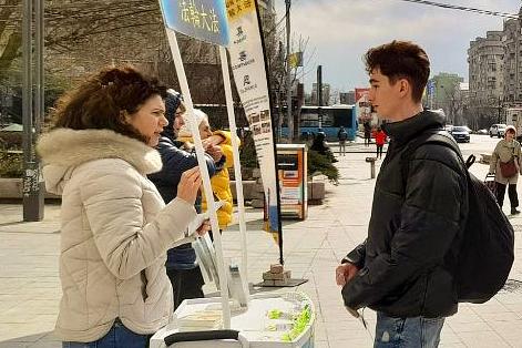 Na informativnom štandu praktikanata na trgu Unirii u Bukureštu 11. marta, mladić (desno) je izrazio svoje divljenje onim što rade.
